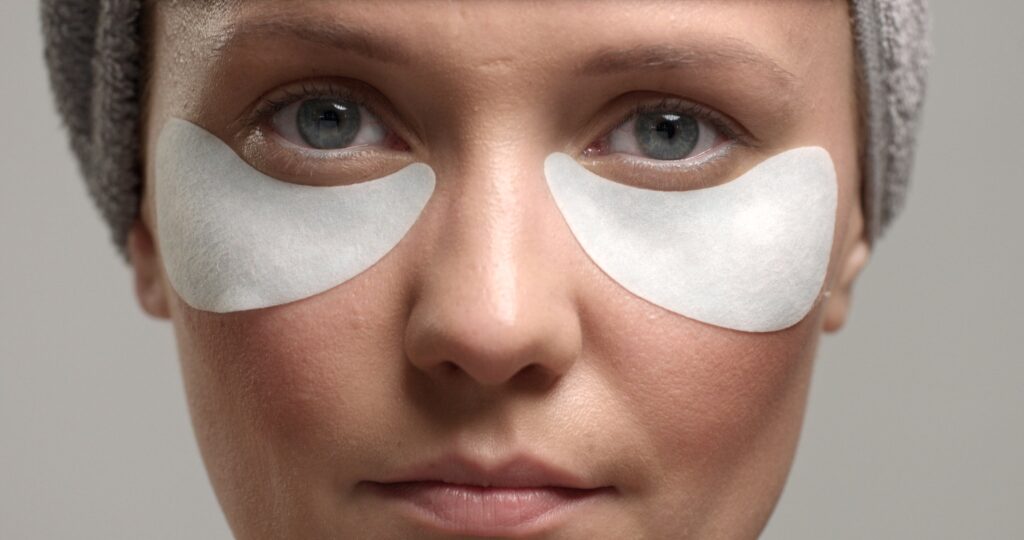 Una mujer echa y derecha haciéndose un tratamiento de ojeras